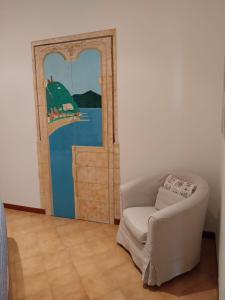 une chambre avec une chaise et une porte avec un tableau dans l'établissement La casa di Via Musso, à Noli