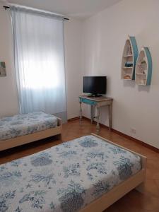 two beds in a room with a tv and a table at La casa di Via Musso in Noli