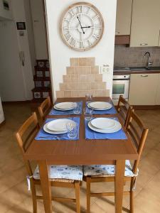 a wooden table with chairs and a large clock on the wall at La casa di Via Musso in Noli +20 photos