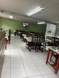 a dining room with tables and chairs and a tv at Pousada do Genesio in Petrópolis