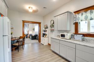 a kitchen with white cabinets and a dining room at Central Chanute Historic Home with Porch! in Chanute