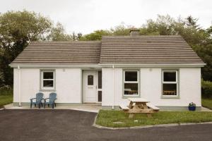 Casa blanca con mesa de picnic y 2 sillas en Donegal Estuary Holiday Homes en Donegal