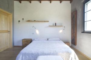 una camera bianca con un letto e una finestra di Coroncina a Belforte del Chienti
