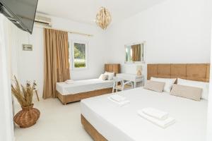 Cette chambre blanche comprend deux lits et un canapé. dans l'établissement Theo Bungalows Boutique Hotel, à Kriopigi