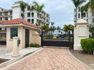 a black gate in front of a building with palm trees at The Country Club Residences at Grand Reserve in Rio Grande