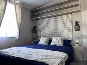una camera da letto con un letto con lenzuola blu e una finestra di Porthcurno 4, Silverbow Country Park a Perranzabuloe