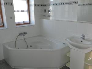 La salle de bains blanche est pourvue d'une baignoire et d'un lavabo. dans l'établissement Ferienwohnung Holtenau, à Altenholz