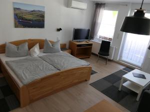 Schlafzimmer mit einem Bett, einem TV und einem Tisch in der Unterkunft Ferienwohnungen und Appartements - Haus Budinger in Alf