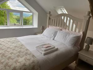 a bedroom with a bed with white sheets and a window at Pippin Lodge in Llanwrda