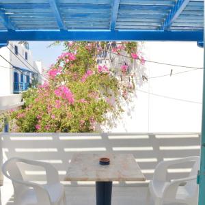 einen Tisch und Stühle auf einer Terrasse mit rosa Blumen in der Unterkunft Asiminas in Naxos Chora