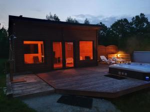 a small cabin with a deck and a hot tub at Mana Village - Jacuzzi & Sauna in Barłomino