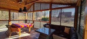 a dining room with a table and chairs on a porch at Pietraszówka in Piertanie