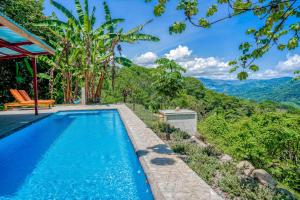 a swimming pool in a villa with mountains in the background at Casa Garrobo in Dominical