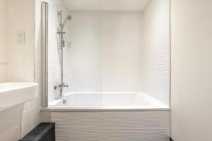 a white bathroom with a tub and a sink at Luxury One Bedroom Serviced Apartment in the Heart of Bedford in Bedford