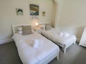 Duas camas num quarto com lençóis e almofadas brancos em Lake House Loft em Windermere