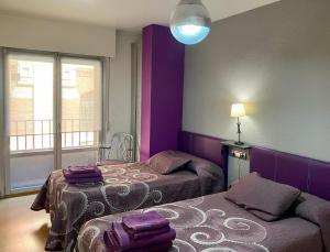 a purple room with two beds and a lamp at Apartamento Berria in Pamplona