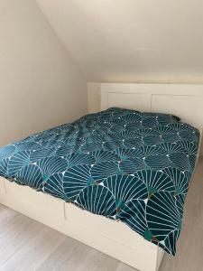 a bed with a blue and white comforter at Bel appartement cosy proche de la frontière Suisse in Villers-le-Lac