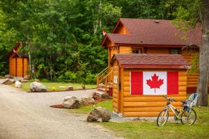 Una bicicleta estacionada al lado de una cabaña con una bandera canadiense. en Lakepoint Cottage Resort en Killaloe Station