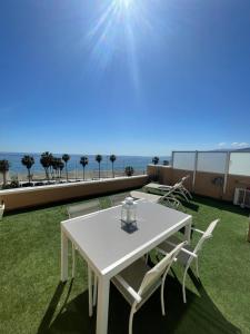 una mesa blanca y sillas en un balcón con vistas al océano en Coqueto estudio-ático EN PRIMERA LÍNEA DE PLAYA CON PRECIOSAS VISTAS AL MAR en Almería