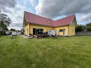 a yellow house with a red roof on a yard at Metsa Apartments in Pärnu