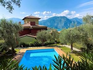 a pool in front of a house with mountains in the background at Sun Beth's house in Brenzone sul Garda