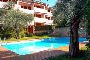 a swimming pool with a tree in front of a building at Sun Beth's house in Brenzone sul Garda