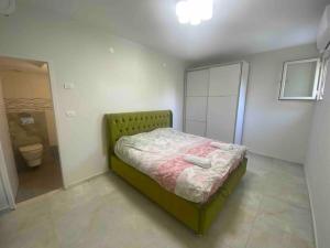 a small bedroom with a green bed and a bathroom at בית נופש בוטיק - Boutique holiday home in Bayit Wegan