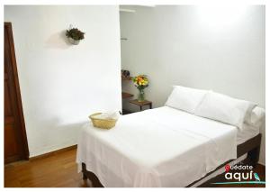 a bedroom with a white bed with a basket on it at Quedate Aqui Barichara - El Original in Barichara