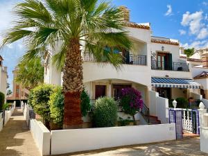 a palm tree in front of a building at Gound Floor Bungalow Jumilla III Playa Flamenca in Orihuela Costa