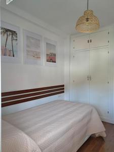 Habitación blanca con cama y lámpara de araña. en Apartamento con encanto y vistas al mar, en Torre de Benagalbón