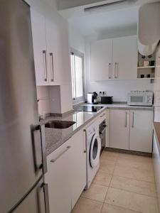 uma cozinha com armários brancos, um lavatório e uma máquina de lavar louça em Apartamento con encanto y vistas al mar em Torre de Benagalbón