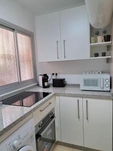 uma cozinha com armários brancos e um micro-ondas em Apartamento con encanto y vistas al mar em Torre de Benagalbón