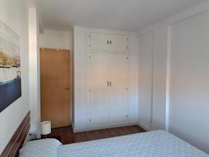 Dormitorio blanco con cama y armario en Apartamento con encanto y vistas al mar, en Torre de Benagalbón