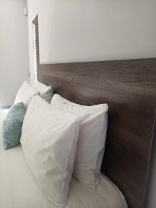 a bed with white pillows and a wooden headboard at Olive Exclusive in Gaborone