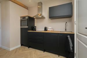 a kitchen with black cabinets and a sink and a microwave at appartement-gratis parkeren -bij strand en in het centrum in Noordwijk