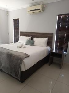 a bedroom with a large bed with a wooden headboard at Olive Exclusive in Gaborone