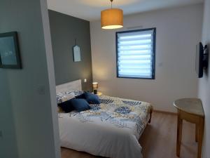 a bedroom with a bed with blue pillows and a window at Sweet home 25mn du Puy du Fou in Cholet +15 photos