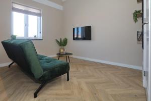 un salon avec une chaise verte et une télévision dans l'établissement appartement-gratis parkeren -bij strand en in het centrum, à Noordwijk
