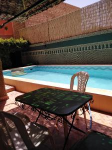 a table and chairs next to a swimming pool at Villa Eden in Ouarzazate