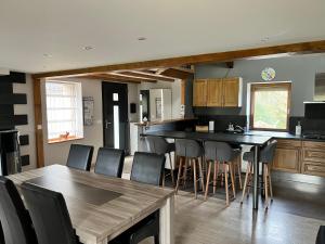 a kitchen with a table and a bar with chairs at Maison de campagne in Moulin-Mage