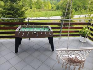 a ping pong table on a patio with a swing at Holiday Home Čančarević in Ravna Gora