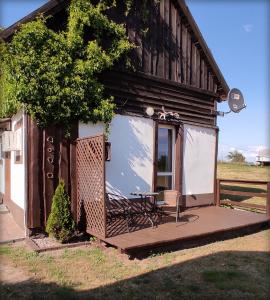 una pequeña casa con una mesa y un banco en un porche en Domki letniskowe, en Mikołajki