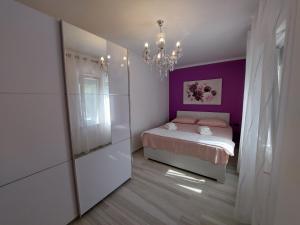 a bedroom with a bed and a purple wall at Apartments Rajna in Čižići