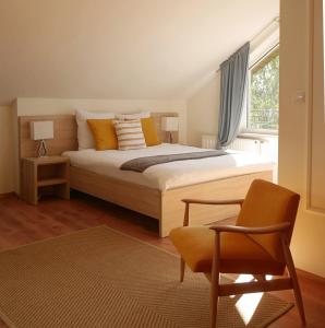 a bedroom with a bed and a chair and a window at Willa Pod Lasem in Tupadły