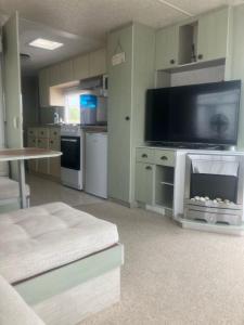 a living room with a large tv and a kitchen at Hollie’s Hemsby holidays - static caravan in Hemsby