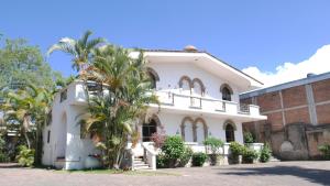 una casa blanca con una palmera delante de ella en Hotel Hacienda las Higueras, en Tepic
