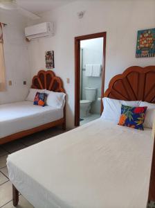 ein Schlafzimmer mit 2 Betten und ein Badezimmer in der Unterkunft Hotel Villa Tulipanes in Zihuatanejo
