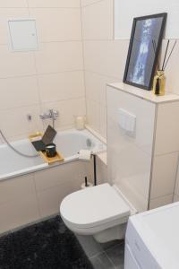 a white bathroom with a toilet and a bath tub at Suite für 4 mit Terrasse im Herzen der Innenstadt in Schwerin