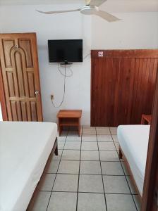 um quarto com duas camas e uma televisão e uma porta em Hotel Villa Tulipanes em Zihuatanejo