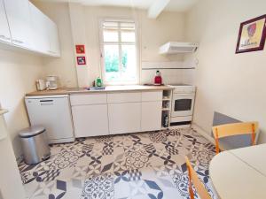 kuchnia z białymi szafkami, zlewem i oknem w obiekcie T2 cosy centre ville w mieście Luchon